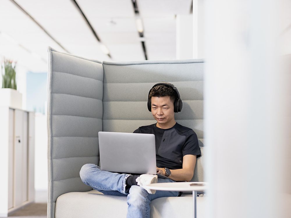 Un empleado de Henkel con auriculares trabaja concentrado en su computadora portátil. 