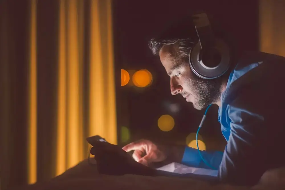 Persona con auriculares trabajando con equipos electrónicos en un ambiente oscuro.