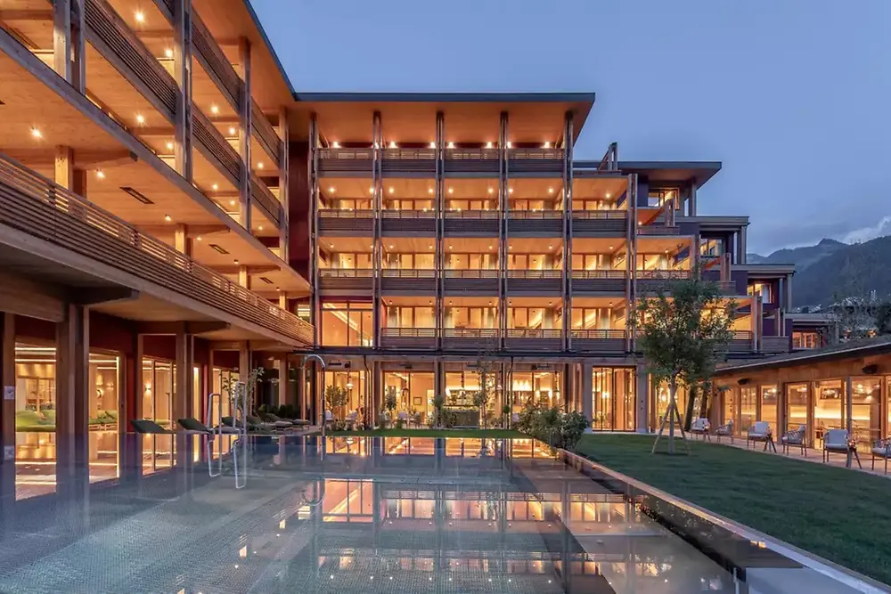 Edificio comercial moderno con exterior iluminado y estanque reflectante al anochecer.