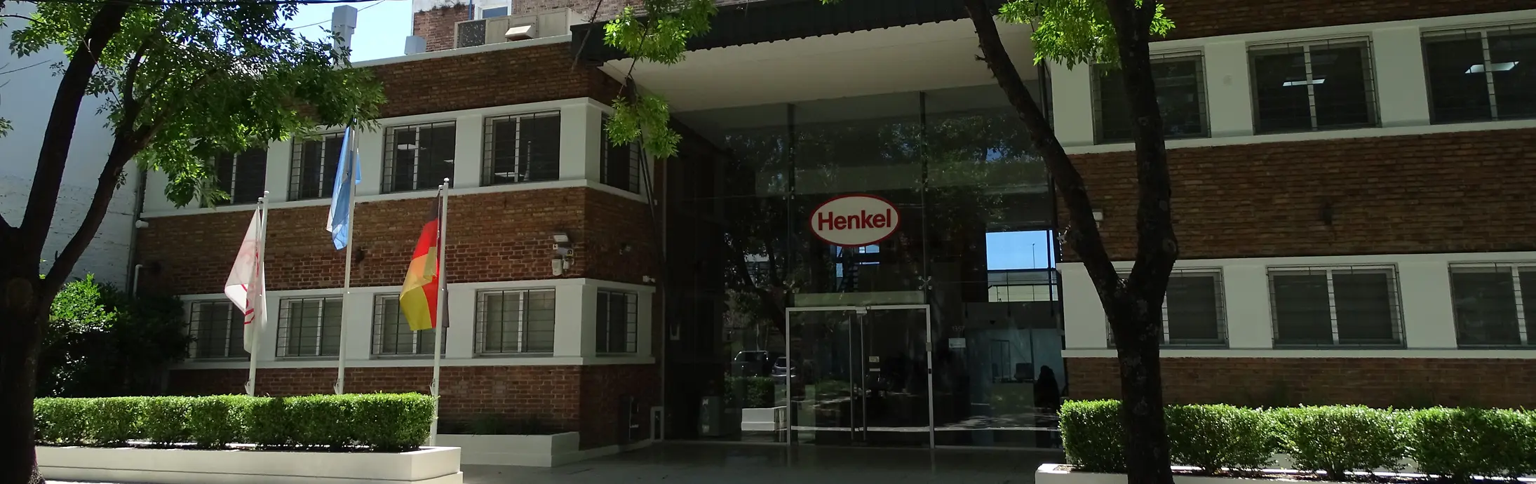 Fachada de las oficinas de Henkel Argentina en San Isidro, con las banderas de Henkel, Argentina y Alemania (izquierda a derecha).